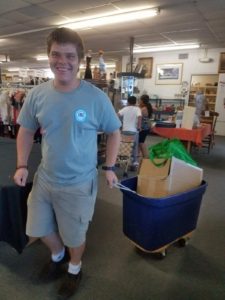 A boy pulls a cart full of boxes.