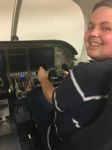 Chris smiles as he plays in an airplane simulator.